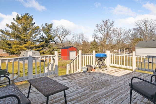 wooden deck featuring a yard, an outdoor structure, area for grilling, and a storage unit