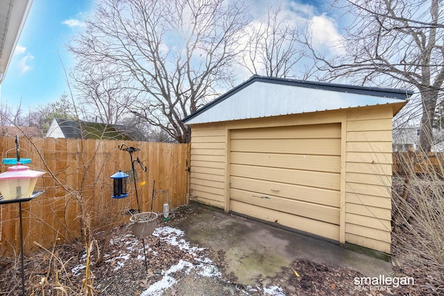 detached garage featuring driveway and fence