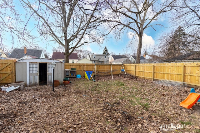 view of yard with a storage shed, a playground, a fenced backyard, and an outdoor structure