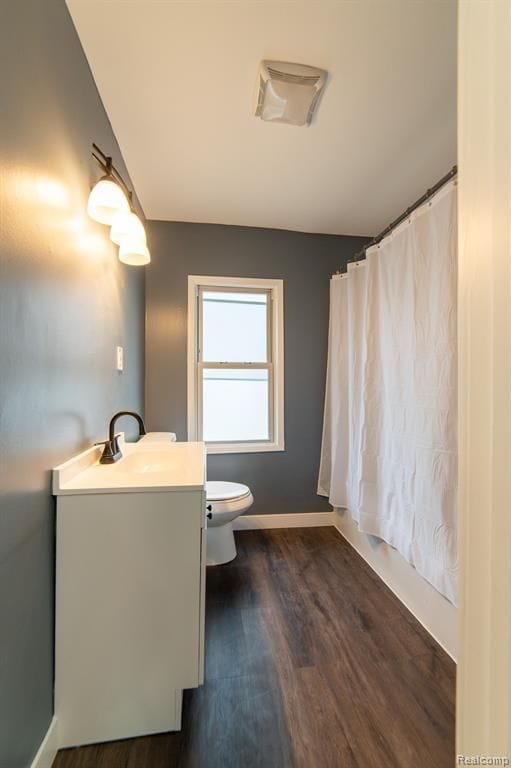 full bathroom featuring a shower with curtain, toilet, wood finished floors, baseboards, and vanity