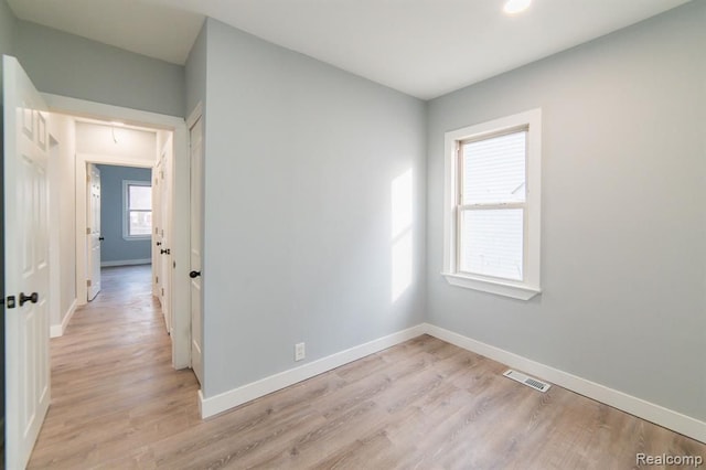 unfurnished room with attic access, baseboards, visible vents, and light wood finished floors