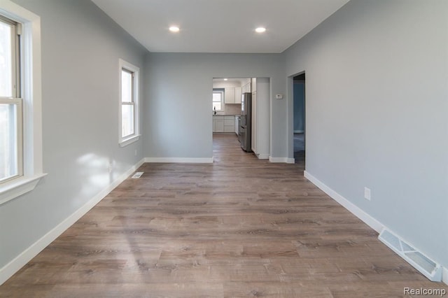 hall featuring visible vents, recessed lighting, baseboards, and wood finished floors