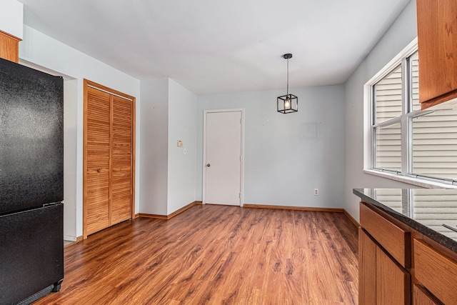 unfurnished dining area with baseboards and wood finished floors