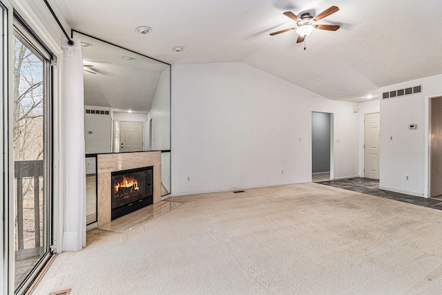 unfurnished living room with visible vents, a ceiling fan, a tile fireplace, lofted ceiling, and carpet