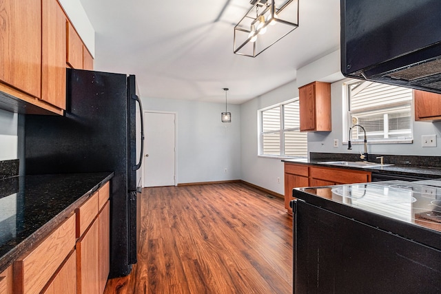 kitchen with black appliances, dark wood-style flooring, brown cabinetry, and a sink