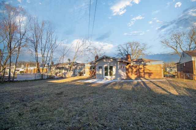 back of property featuring a yard, a patio area, fence, and a chimney