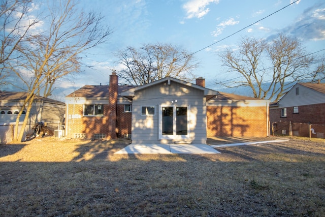 rear view of house with a chimney, a lawn, and brick siding