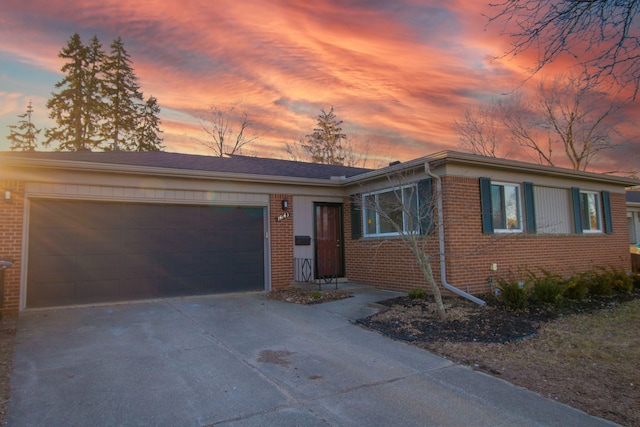 view of front facade with driveway, brick siding, and an attached garage