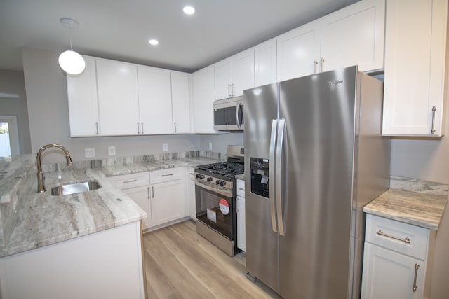 kitchen with stainless steel appliances, white cabinetry, a sink, and light stone counters