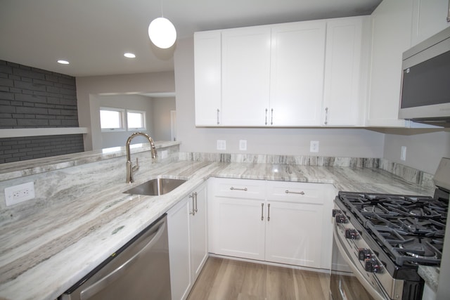 kitchen featuring light stone countertops, white cabinetry, appliances with stainless steel finishes, and a sink