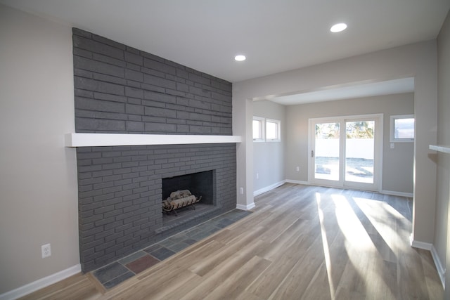 unfurnished living room with recessed lighting, a fireplace, baseboards, and wood finished floors