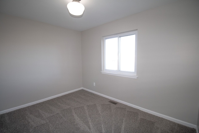 empty room featuring carpet floors, visible vents, and baseboards