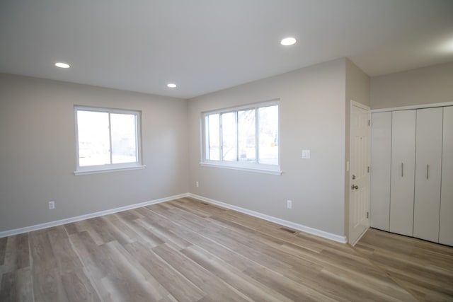 unfurnished bedroom with recessed lighting, light wood-style flooring, and baseboards