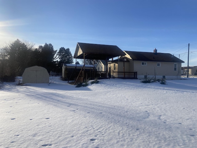 snow covered back of property with a storage shed and an outbuilding