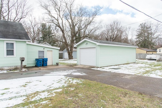 detached garage featuring fence and aphalt driveway