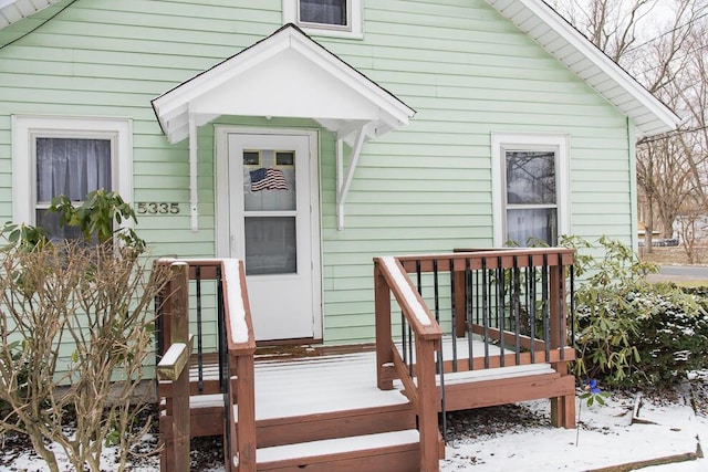 snow covered property entrance featuring a deck