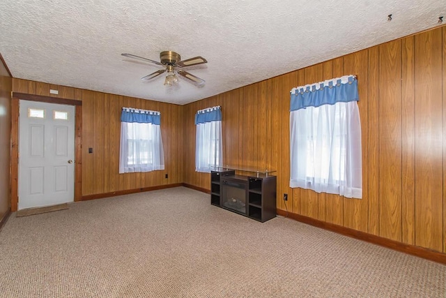 interior space with wooden walls, carpet, ceiling fan, and a textured ceiling