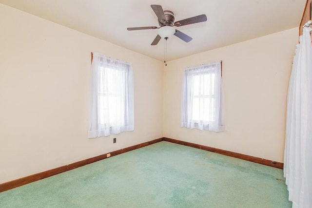 carpeted empty room featuring ceiling fan and baseboards