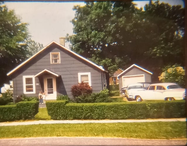 bungalow with a garage and an outbuilding