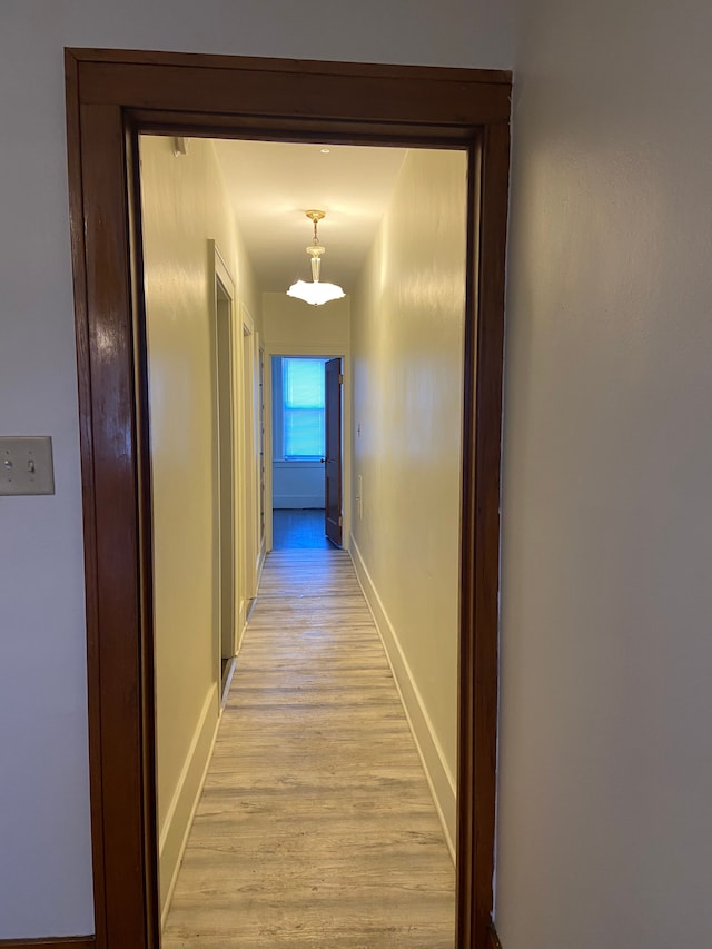 corridor with light wood-type flooring and baseboards