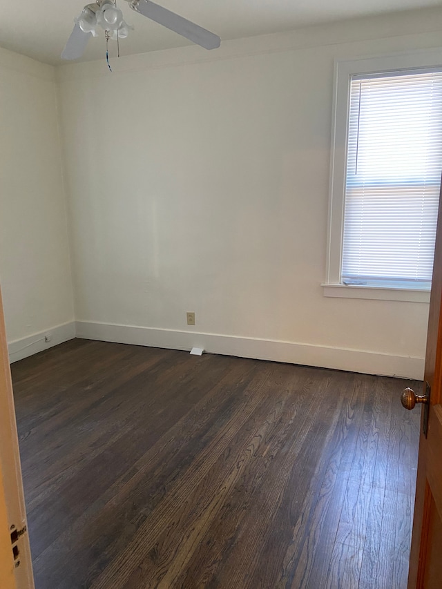 empty room featuring a ceiling fan, dark wood-style flooring, and baseboards