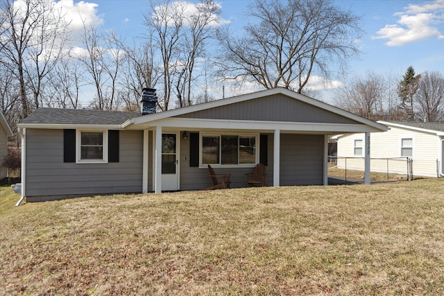 view of front of home featuring fence, roof with shingles, a front yard, a chimney, and a carport