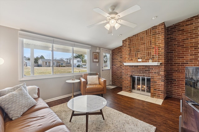 living area featuring ceiling fan, wood finished floors, a fireplace, and vaulted ceiling