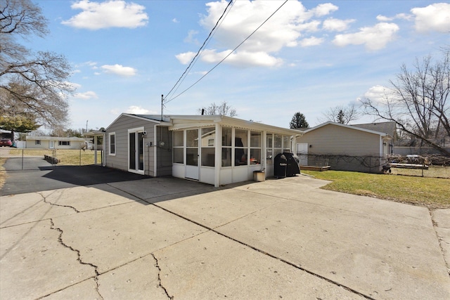 view of front of property with fence, concrete driveway, a front yard, and a sunroom