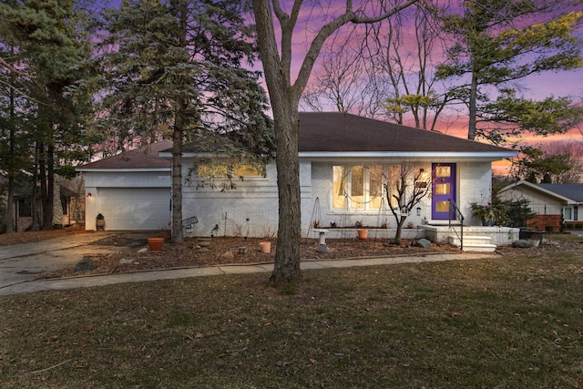 single story home with brick siding, an attached garage, driveway, and a yard