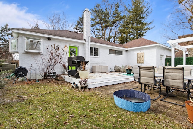 back of property with outdoor dining space, a lawn, brick siding, and a chimney