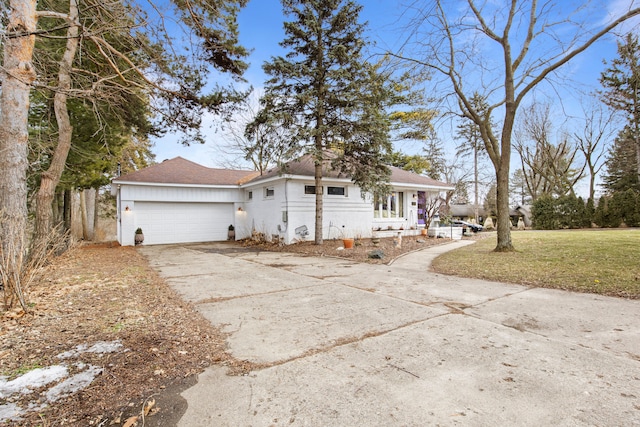 ranch-style home with a front yard, an attached garage, and driveway