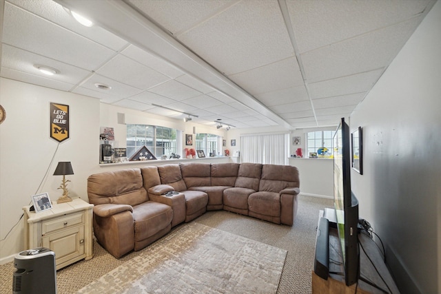 living room featuring light carpet, a wealth of natural light, baseboards, and a drop ceiling