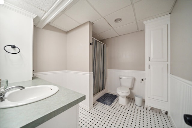 full bath with a paneled ceiling, wainscoting, a shower stall, and toilet