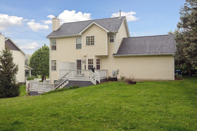 rear view of property with a yard, a shingled roof, a chimney, and a wooden deck