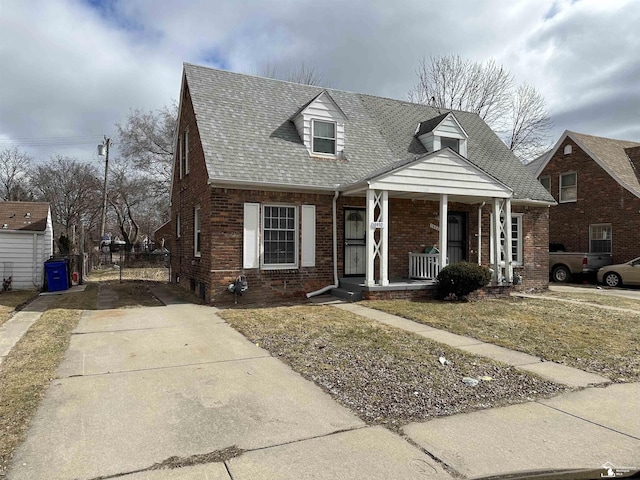 view of front facade featuring brick siding, roof with shingles, and a porch