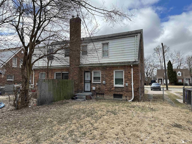 back of property featuring brick siding, fence, and a chimney