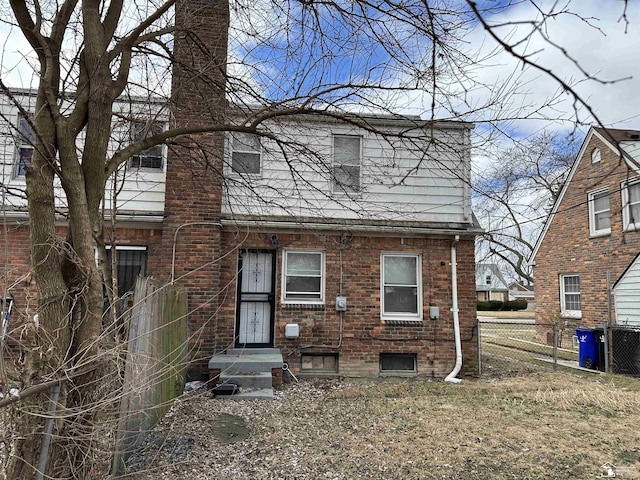 view of front of home featuring brick siding and fence