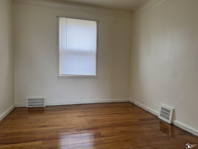 unfurnished room with hardwood / wood-style flooring, visible vents, and baseboards