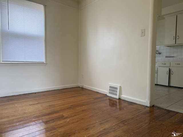 spare room with light wood-style flooring, visible vents, and baseboards