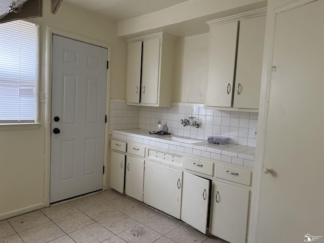 kitchen with tile countertops, white cabinets, decorative backsplash, and a sink