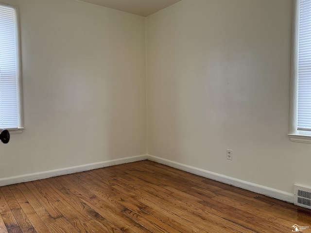 unfurnished room with visible vents, baseboards, and wood finished floors