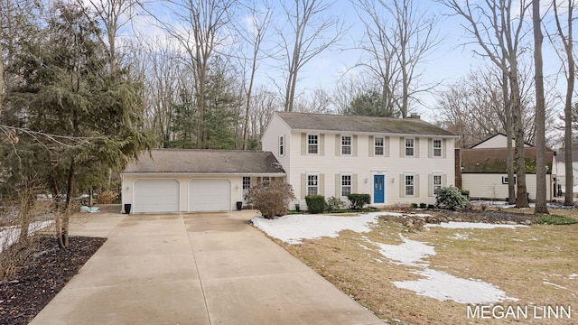 colonial home featuring a garage, a chimney, and concrete driveway