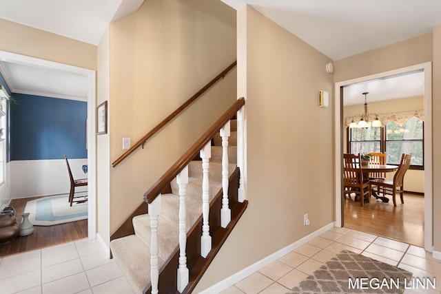 stairway with baseboards, tile patterned flooring, and an inviting chandelier