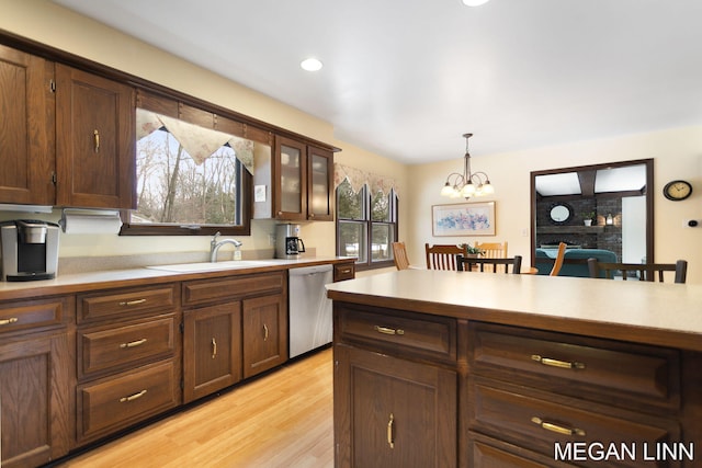 kitchen featuring dishwasher, light countertops, a brick fireplace, and a sink