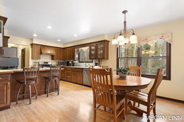 dining area with an inviting chandelier, baseboards, light wood finished floors, and recessed lighting