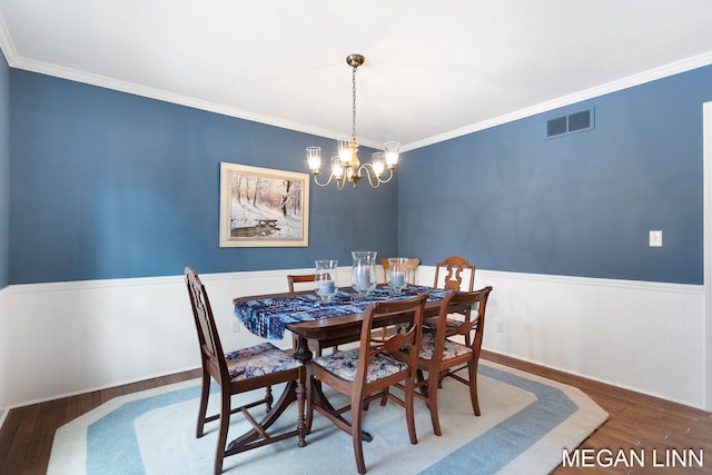 dining space with visible vents, wainscoting, ornamental molding, wood finished floors, and a notable chandelier