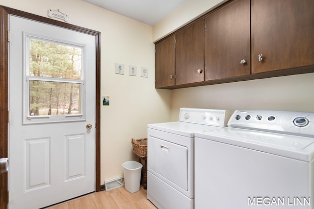 laundry room featuring visible vents, cabinet space, light wood-style flooring, washer and dryer, and baseboards