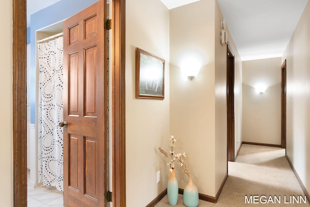 hallway with light colored carpet and baseboards