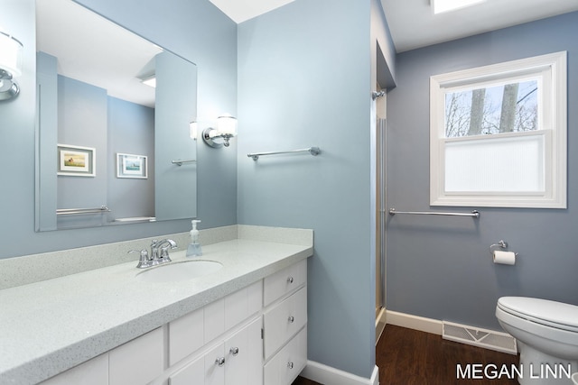 bathroom with visible vents, toilet, vanity, wood finished floors, and baseboards