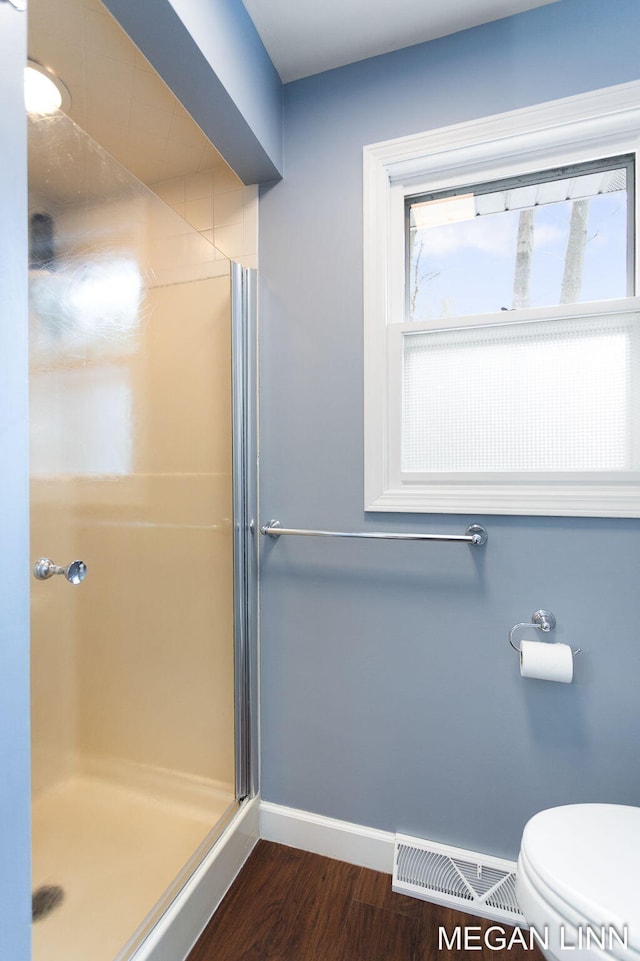 bathroom with a stall shower, baseboards, visible vents, toilet, and wood finished floors